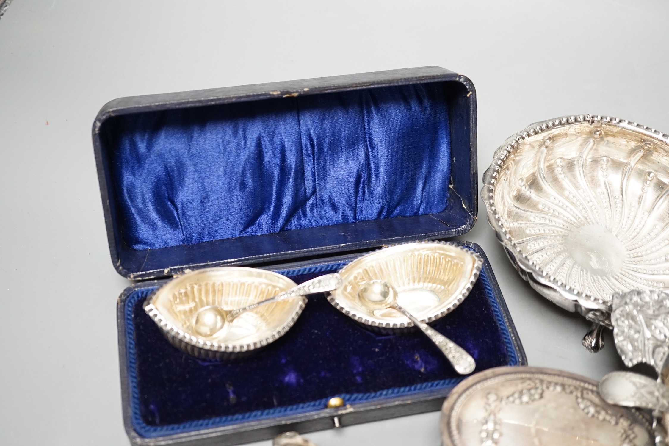 A Victorian repousse silver two handed bowl, one other silver bowl, a silver sifter spoon, four silver mounted glass toilet jars, a silver dwarf candlestick and a cased pair of silver salts.